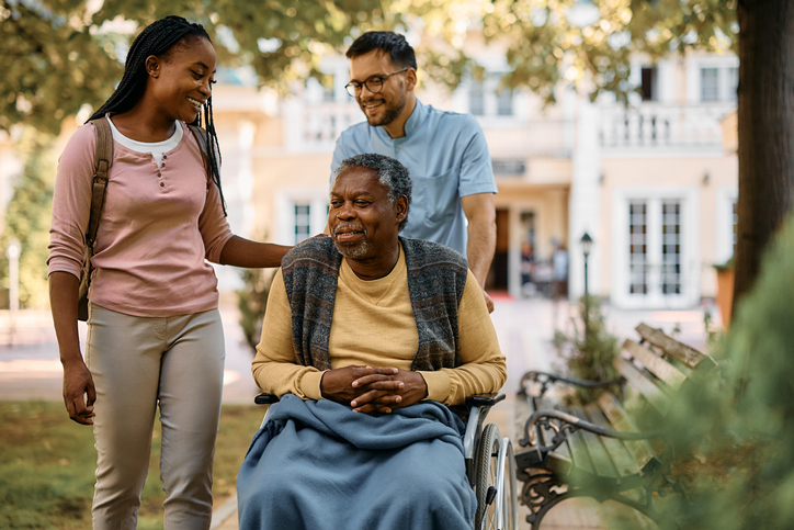 Happy black woman visiting her senior father in nursing home.