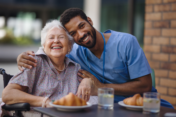 Caregiver having breakfast with his client at cafe.