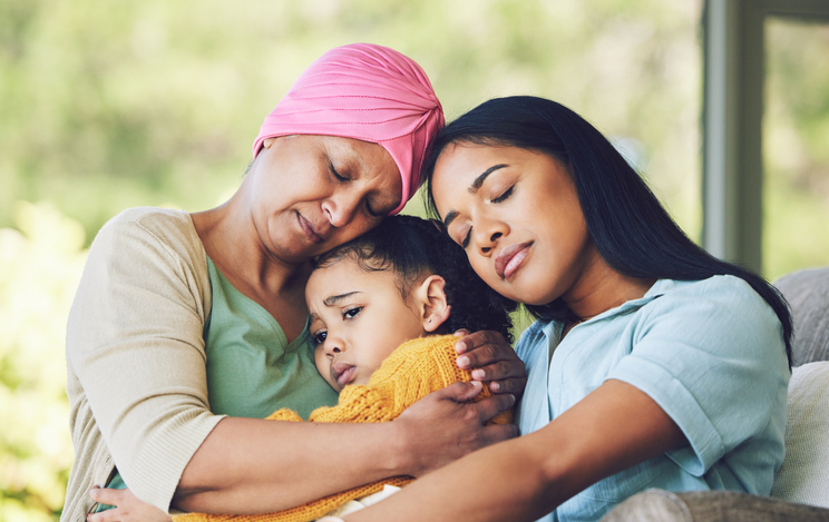 Sad, hug and cancer with a family in a house for support, care and love on living room sofa. Unhappy, chemotherapy and mother and child with sick grandmother for help, hope and solidarity at hospice